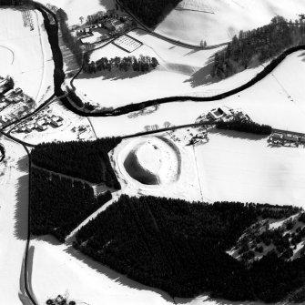 Oblique aerial view of Doune of Invernochty centred on the remains of the motte, chapel, castle, building and observation post with Bellabeg and Strathdon Parish Church adjacent, taken from the NW.