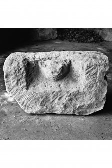 View of dressed sandstone block with coped sides and bearing a cat like head in high relief, held in the garage behind the manse.