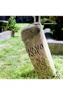 View of chamfered edge on rear face of reused medieval gravestone set on end.