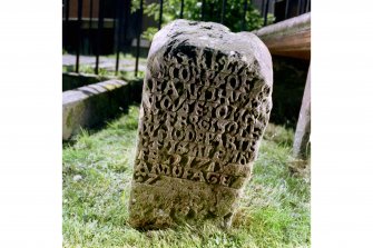 View of eighteenth century inscription on front face of reused medieval gravestone set on end.