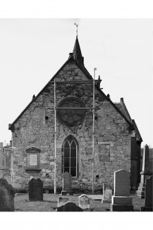 View of East gable with scaffolding and gravestones.