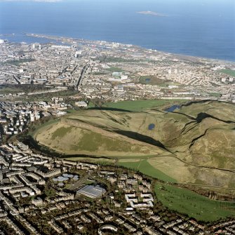 Oblique aerial view of Edinburgh centred on Holyrood Park, taken from the S.