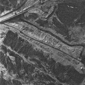 Oblique aerial view, taken from the SW, showing the remains of ironworks, lime kilns, coke ovens and workers' rows in the centre and bottom of the photograph, and a large area of bell pits in the centre and top right-hand corner.