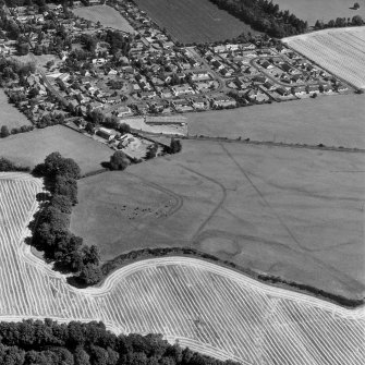 Dalginross, oblique aerial view, taken from the W, centred on the cropmarks of the Roman Fort. The Roman Temporary Camp is visible in the centre right of the photograph.