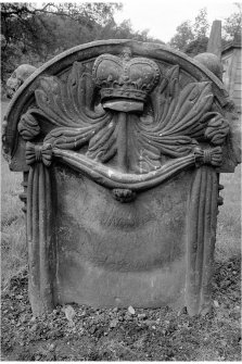 View of gravestone 'William Drover d. 1742' (Drover). Showing a central crown and hammer with fronds and a swag surrounding the inscription. Two skulls on sides of stone.