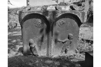 View of headstone for J.P. C.B., 1763: two panels with a figure in each, sun over left figure, moon over right.
