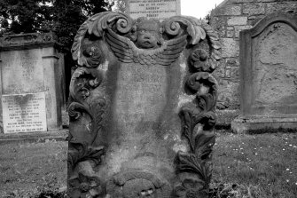 Edinburgh,  Dell Road, Colinton, Colinton Parish Church, Churchyard.
View of East face of Gravestone of 1743, with a scrolling foliated border with winged soul at the top, and a skull with a 'Memento Mori' ribbon between two large flowers at the base.