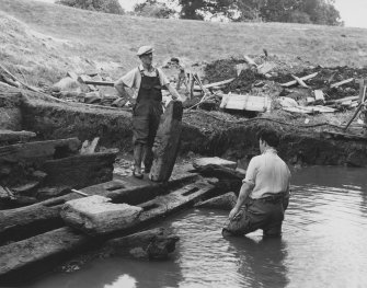 Excavation photograph: View of timbers of bridge found in moat, partial reconstruction.
