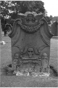 Aberlady churchyard.
Inscription illegible. Winged cherub at top of stone, cornucopia beneath. Skull and single bone between figures of sower and reaper.