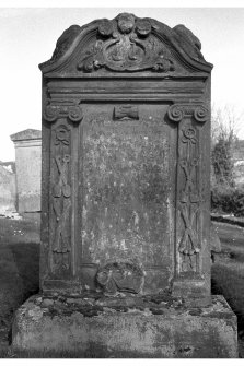 View of gravestone. James Ranken d.1782. Merchant's scales within pediment. Inscription bordered by crossed spades and crossbones suspended on ribbons. Skull in profile at foot of inscription.