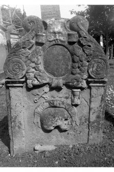 Detail of tombstone.
John Smith, d.1724. Reverse face of gravestone showing Green Man and cornucopia at top of stone. Crossed spades, hourglass, skull, bone and 'Momento Mori' scroll beneath.