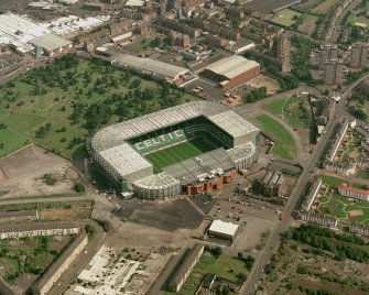 Oblique aerial view, taken from the W, centred on Celtic Park football stadium, and showing the Eastern Necropolis graveyard in the centre left of the photograph.