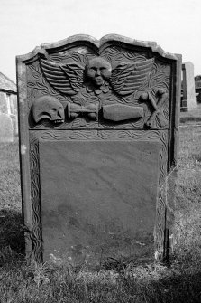 Gravestone commemorating Isobel McLunie, d.1769. Winged cherub; skull in profile, coffin, winged hourglass, crossbones.