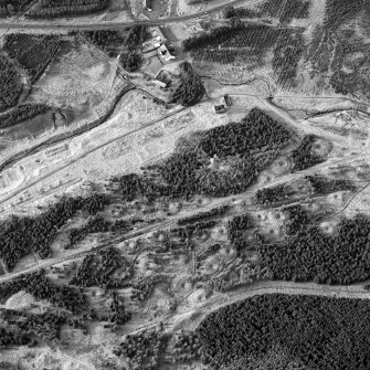 Scanned image of oblique aerial view, taken from the ESE, showing the remains of workers' rows and buildings across the centre of the photograph, lime kilns in the centre left, and a large area of bell pits in the bottom half. Digital image of C41142.