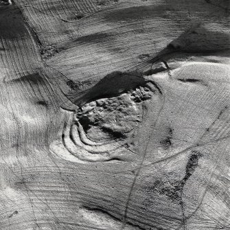 Oblique aerial view centred on the remains of the fort with rig and field banks adjacent, taken from the SW.