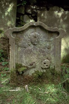 Minto House, Church and Graveyard.
18th Century gravestone for John Turnbull and son. View of front of gravestone. The carving is of an Angel of death, robed with bone, skull and an hourglass. Over the top of the stone is inscribed, memento mori.