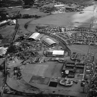 Dumfries, Heathhall Airfield, oblique aerial view, taken from the NW, centred on three hangars and various other buildings.