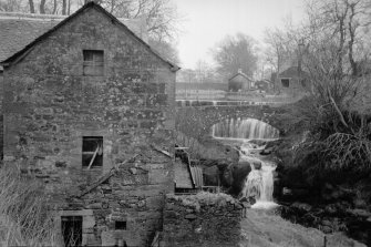 View from WNW showing part of W front of mill with bridge and mill dam in background