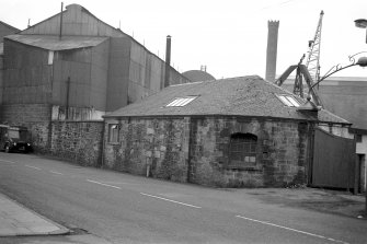 View from SSW showing WSW front and part of SSE front of N entrance lodge with foundry in background