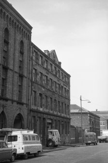 View from S showing ESE front of N block with part of S block of paint warehouses in foreground and Glasgow Copper Works in background