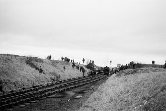 Distant view from NE showing train at station with people running in all directions