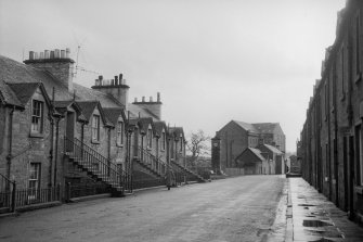 View looking ESE showing part of SW front of houses on N side of Teith Road with memorial, workshops and main block of mill in background