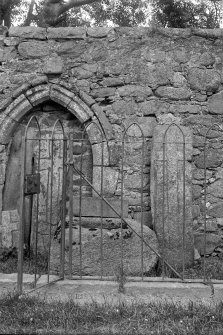 View of sculptured stones and arched doorway in railed enclosure.
Original negative captioned: 'Sculptured Stones and old Font. Church of Tullich near Ballater July 1902'.