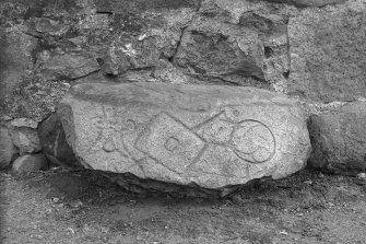 View of Pictish symbol stone lying on its side against a stone wall.
Original negatives captioned: 'Sculptured Stone at Newton of Lewesk, Rayne July 1915'.

