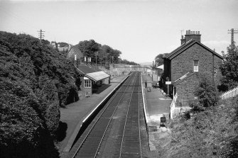 View looking ENE along track with up platform building on left, down platform building on right and footbridge in background