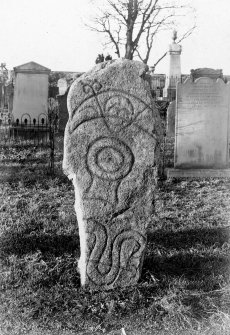 Inverurie Pictish symbol stone no.1, set upright.
Original print captioned: 'Sculptured Stone in Inverurie Churchyard No.I. Block of granite with 4 symbols viz. (1) Crescent and rod (2) Mirror case, (3) Serpent and rod (4) Double disc (on portion below ground). Figures in Stuarts 'Sculptured Stones  of Scotland' Vol. 1 pl. 113, and in 'Early Christian Monuments of Scotland' page 168.'