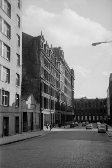 View from N showing WNW front of warehouse with number 24 in foreground and factory and part of 117 Ingram Street in background