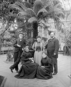 View of the conservatory, Peebles Hydropathic Hotel, with a group of people, possibly the hotel manager Albert Max Thiem and family.

