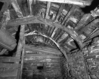 Interior of cruck-framed byre showing roof detail, roof groundwork and cruck-frame in foreground composed of re-used ships timbers; The Buaile, Ramscraigs.