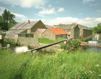 General view from SSW of S corner of block of buildings at centre of site, with aerator machines to add air to water, installed by fish farm to improve standard of water before return to the Ettrick Water