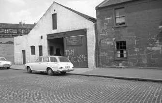 View from W showing WNW front of workshop with part of house in foreground