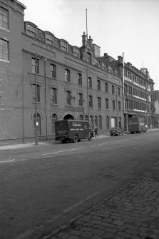View from S showing ESE front of rubber works with warehouse in background
