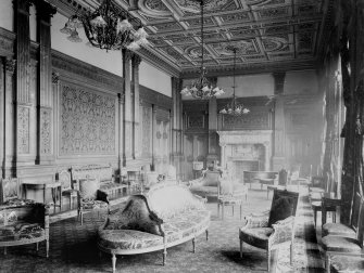 Interior-general view of drawing room with sofas and chairs, also showing patterned wallpaper and marble fireplace
