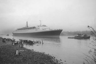 View looking SE showing QE II on River Clyde approaching Bowling with remains of pier in foreground