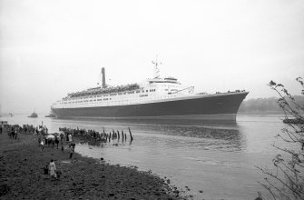 View looking South East showing QE II on the River Clyde approaching Bowling with remains of pier in foreground.