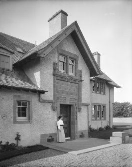 View of entrance doorway with woman standing to left of door, also showing inscription above door reading 'Welcome the Coming and Speed the Parting Guest'
