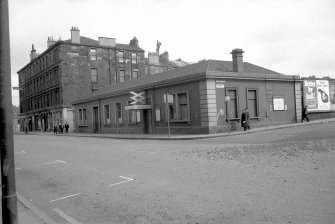 View from SSW showing WSW and S fronts of station booking office with tenements and shops in background