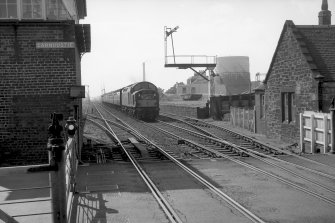 View looking W showing train approaching with original station building on right and level crossing in foreground