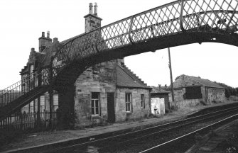 View from N showing part of NW and NE fronts of down platform building with goods shed in background and part of footbridge in foreground