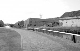 View from SE showing ESE and SSW fronts of E block with W block of foundry in background and part of lancet-windowed building of workshops in foreground