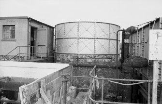 View from WSW showing curved WSW front of S acid tank with part of hut on left and water tank on right