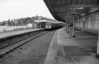 View looking NE showing train with part of main station building on left and part of platform shelter on right