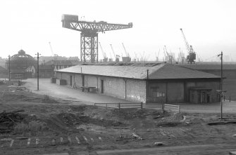 View from NE showing NNE and ESE fronts of E goods shed with crane in background