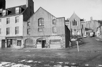 View from SE showing SSE front of warehouse with church in background and part of numbers 2-3 Trinty Quay on left