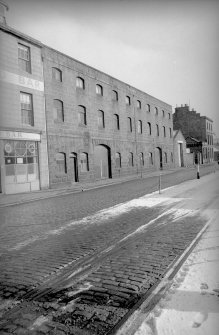 View from W showing SSW front of warehouse with part of numbers 77-80 in foreground