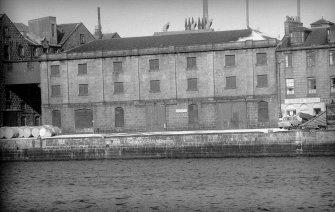 View from SSW showing SSW front of E building with part of main building of flour mill on left and part of numbers 77-80 on right